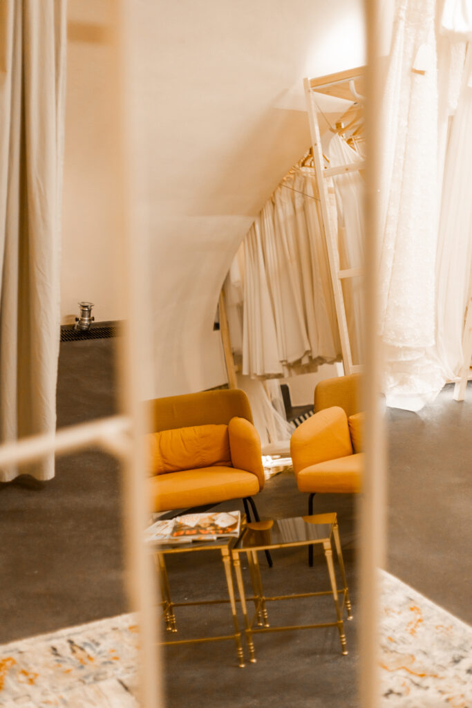Anproberaum im Atelier Unique Bridal Concept in Iphofen. In einem Spiegel sieht man die orangen Ikea Sessel und eine Reihe an Kollektionskleidern von Lisa Dörr Couture.