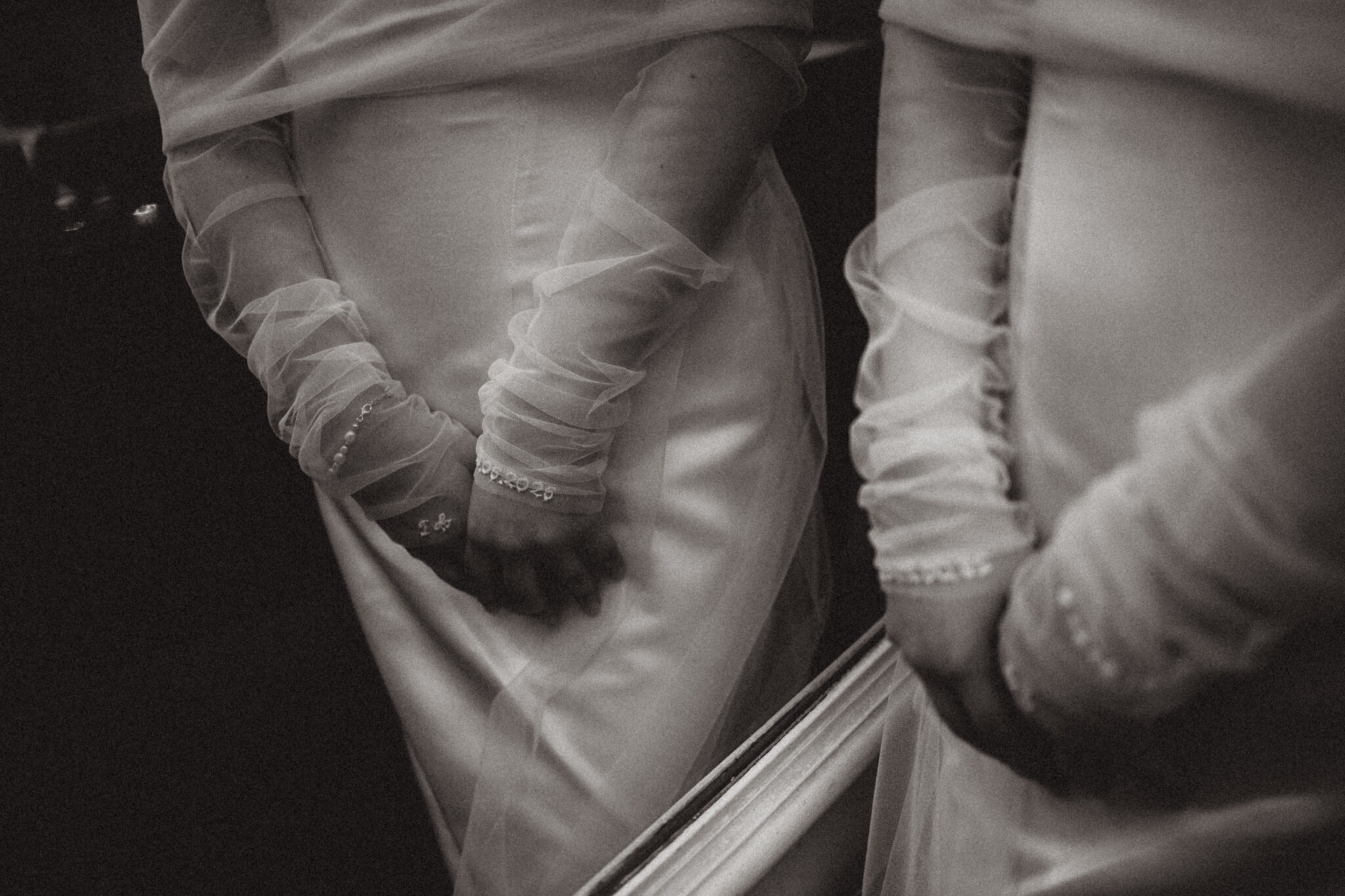 Braut vor einer Spiegelwand lehnt an ein Grand Piano in einer Hochzeitslocation, enges Duchesse Seidenkleid mit Jäckchen Top aus Tüll