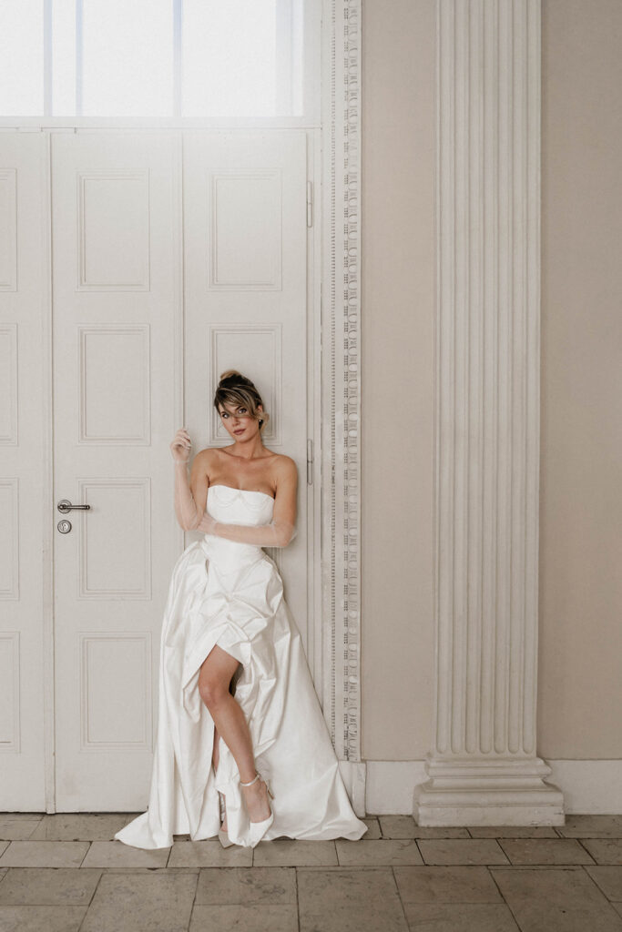 Braut im Brautkleid Winnifred, Corsagenkleid mit Perlenverzierung, Spitz zulaufender Corsage und trendigem gerafften Rock mit sichtbarem Bein, royal